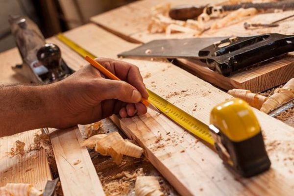 carpenter taking measurement of a wooden plank